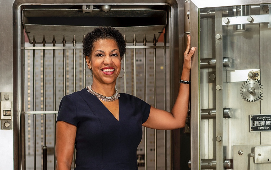 Image of Teri Williams standing in front of an open bank safe.